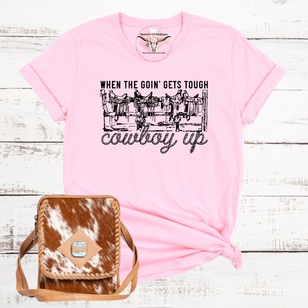 pink short sleeve tee with sublimation graphic design. Saddles on a fence reading When the goin gets tough cowboy up
